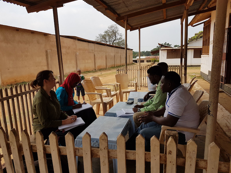 five people sitting outside in a meeting