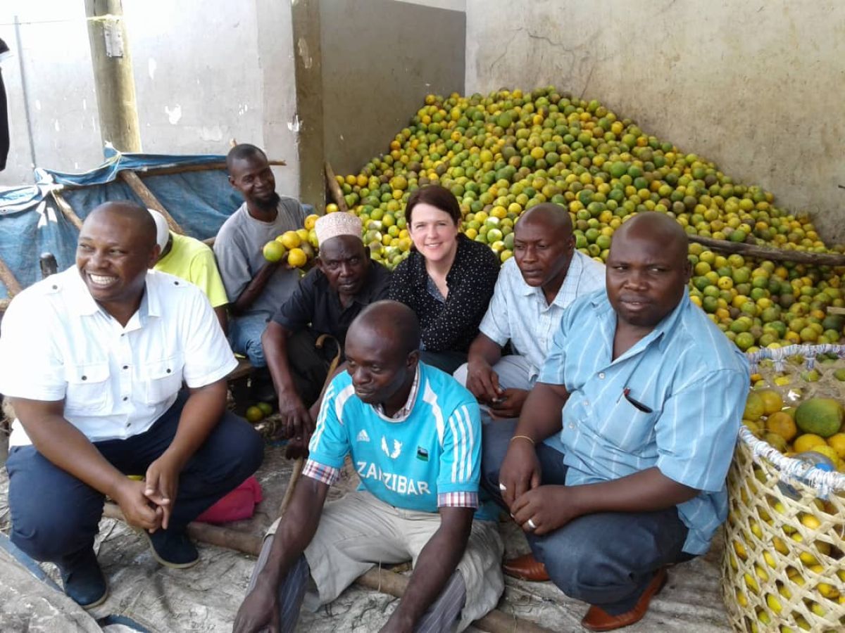 group of people sitting beside large pile of oranges