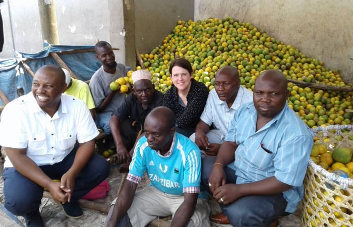 group of people sitting beside large baskets of oranges